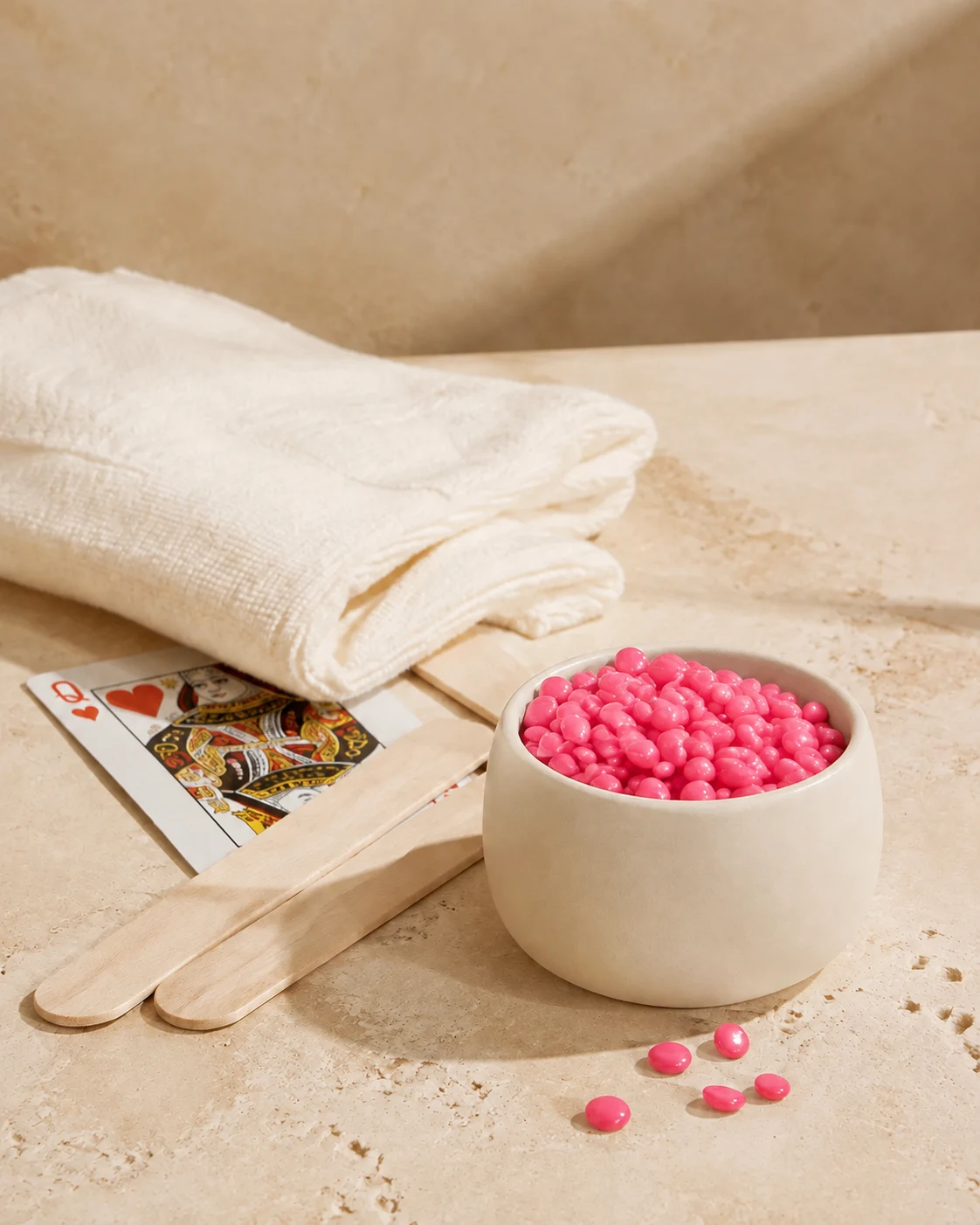 Pink hard wax beads and wooden waxing spatulas